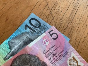 Close-up of Australian 5 and 10 dollar notes on a wooden background.